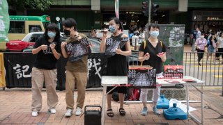 Chow Hang Tung, vice chairperson of the Hong Kong Alliance in Support of Patriotic Democratic Movements of China, left, and other activists at a sidewalk booth showcasing the 1989 Tiananmen Square crackdown in Hong Kong, on Saturday, May 29, 2021.