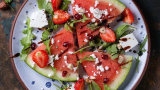 Blue spotted plate with watermelon and strawberry fruit salad with feta cheese, arugula, nuts and balsamic sauce
