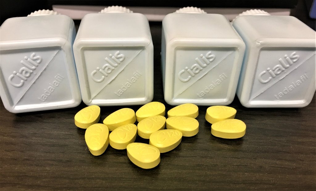 Neon green pills sit scattered on a table, in front of four plastic bottles that read "Cialis." The pills are counterfeits seized by U.S. Customs and Border Protection.