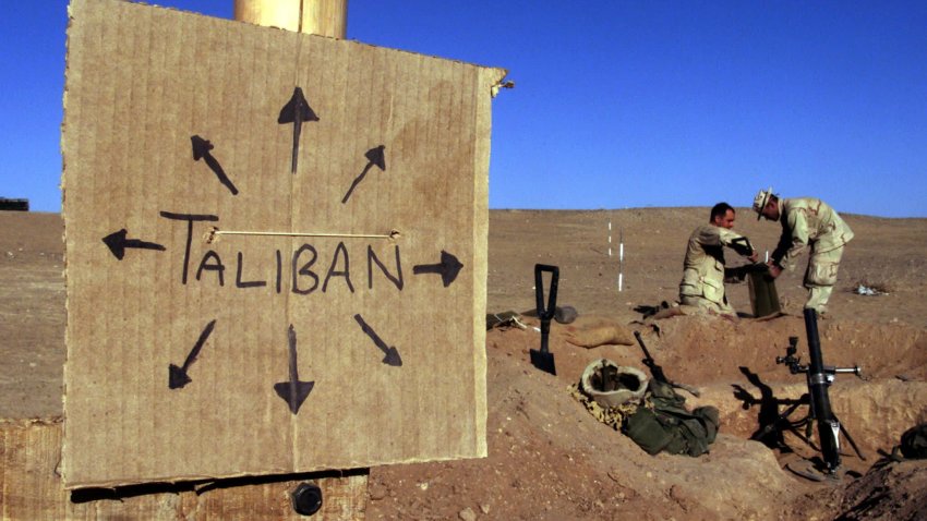U.S. Marines from Charlie 1/1 of the 15th MEU (Marine Expeditionary Unit) fill sandbags around their light mortar position on the frontlines of a U.S. Marine Corps base, near a cardboard sign reminding everyone that Taliban forces could be anywhere and everywhere, in southern Afghanistan December 1, 2001.
