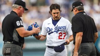 Umpires check the hat and glove of Trevor Bauer #27 of the Los Angeles Dodgers for foreign substances after the first inning against the San Francisco Giants at Dodger Stadium on June 28, 2021 in Los Angeles, California.