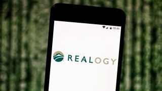 The Realogy Holdings logo is seen displayed on a smartphone.