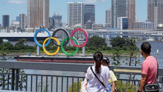A family stands in front of the oversized Olympic rings. The rings stand on a raft in Tokyo Bay in front of the Odaiba district. The 2020 Tokyo Olympics will take place from 23.07.2021 to 08.08.2021.