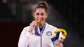 Gold medallist Anastasija Zolotic of the United States bites her medal at a victory ceremony for the women's -57kg taekwondo event during the Tokyo 2020 Summer Olympic Games, at the Makuhari Messe convention center.