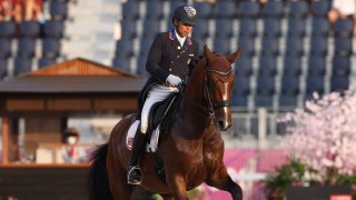 Steffen Peters rides Mopsie, a light brown horse, in a dressage arena