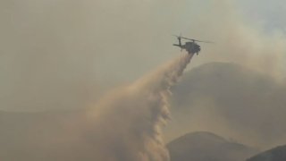 A helicopter drops water on the Tumbleweed Fire.
