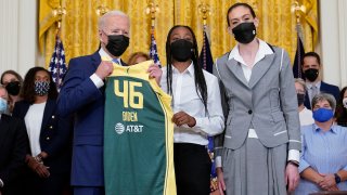 President Joe Biden, left, poses for a photo with Seattle Storm's Jewell Loyd, center, and Breanna Stewart, right, during an event in the East Room of the White House in Washington, Monday, Aug. 23, 2021, to celebrate their 2020 WNBA Championship.