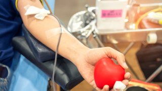 Blood donor at donation, transfusion. Closeup blood donor squeezes the bouncy ball in the form of heart in his hand. Healthcare and charity. Concept image for World blood donor day-June 14.
