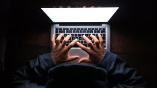 Hooded Hacker Stealing Data From Laptop At Night