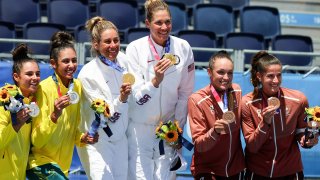 Women's beach volleyball's six medal winners smile and show their prizes