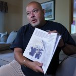Will Jimeno holds the children's book he wrote, "Immigrant, American, Survivor."