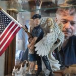 Retired NYPD Officer Mark DeMarco, is seen in a reflection off a display cabinet where he keeps memorabilia from 9/11