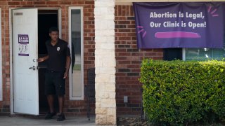 FILE - In this Sept. 1, 2021 file photo, a security guard opens the door to the Whole Women's Health Clinic in Fort Worth, Texas. Even before a strict abortion ban took effect in Texas this week, clinics in neighboring states were fielding more and more calls from women desperate for options. The Texas law, allowed to stand in a decision Thursday, Sept. 2, 2021 by the U.S. Supreme Court, bans abortions after a fetal heartbeat can be detected, typically around six weeks.