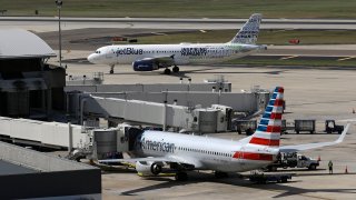 A JetBlue Airbus A320 taxis to a gate Wednesday, Oct. 26, 2016, after landing as an American Airlines jet is seen parked at its gate at Tampa International Airport in Tampa, Fla.