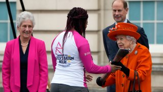 Britain's Queen Elizabeth II hands over the Queen's Baton to the first relay runner Kadeena Cox