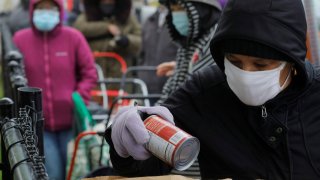 A resident sorts her free groceries as others wait in line at the food pantry of the Fourth Presbyterian Church amid the ongoing coronavirus disease (COVID-19) pandemic, in Boston, Massachusetts, U.S., April 27, 2021.