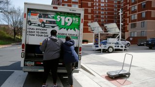 People pushing a U-Haul truck