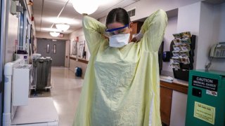 A doctor puts on her protective gear during her shift in the ICU.