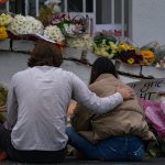 People bring flowers to the memorial sight set up outside of The Gold Spa on March 19, 2021 in Atlanta, Georgia.