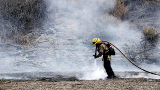 A firefighter puts out hot spots.