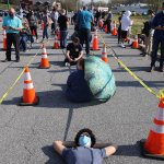 Eugene Chirkov of Bethesda, Maryland, finds a sliver of shade from a traffic cone while waiting in line with people without appointments outside the mass coronavirus vaccination site at Hagerstown Premium Outlets on April 7, 2021, in Hagerstown, Maryland. He is 140th in line.