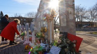 A woman lays flowers at a memorial in Waukesha, Wis., Tuesday, Nov. 23, 2021. She had a daughter who marched in the parade and witnessed the incident. On Sunday an SUV plowed into a Christmas parade killing five people and injuring scores more.