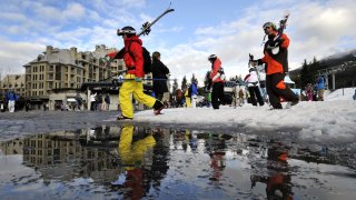 A man carries his skis as snow melts at the limit of the ski slopes in Whistler on February 8, 2010. Whistler Creekside is the Alpine skiing venue of the Vancouver 2010 Winter Olympics. Winter Olympic host city Vancouver saw its warmest January on record, marked by a lack of snow and daffodils in bloom just days before the start of the Games, the Meteorologist Service of Canada said.