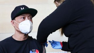 LOS ANGELES, CALIFORNIA – JANUARY 07: A person receives a COVID-19 vaccination dose, during a free distribution of COVID-19 rapid test kits for those who received vaccination shots or booster shots, at Union Station on January 7, 2022 in Los Angeles, California. Thirty new deaths and over 37,000 new cases of COVID-19 were reported by Los Angeles County amid the continued spread of the Omicron variant. (Photo by Mario Tama/Getty Images)