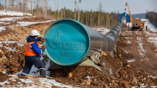 A worker adjusts a Gazprom branded end cap on a section of pipework during pipeline laying operations for the Gazprom PJSC Power of Siberia gas transmission line between the Kovyktinskoye and Chayandinskoye gas fields near Irkutsk, Russia, on Tuesday, April 6, 2021.