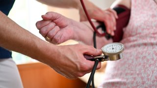 In this file photo, a nurse measures the blood pressure of a resident of a retirement home in her room.