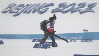 A staff member clears away snow at the National Cross-Country Skiing Centre, Feb. 13, 2022, Zhangjiakou, China. Beijing saw snow for the first time since the start of the 2022 Winter Olympic Games.