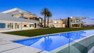 The rear of the home opens to a massive lawn framed by a moat-like water feature and a 400 ft. running track just below it.