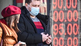 People walk past a currency exchange office in central Moscow on Feb. 28, 2022, with zeros on the scoreboard since there are no three-digit sections on it to display the current exchange rate.