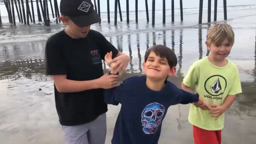 Connor Dalby walks on the beach with his brothers.