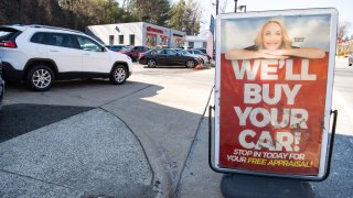 A sign advertises to purchase cars at a used car dealership in Arlington, Virginia, February 15, 2022.