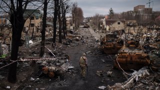 A Ukrainian serviceman walks amid destroyed Russian tanks