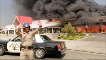 A California Highway patrolman directs raffic around a shopping center engulfed in flames in Los Angeles.