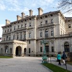 Visitors walk toward an entrance to The Breakers mansion in Newport, R.I.