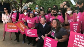 California Gov. Gavin Newsom poses with workers and volunteers on Wednesday, May 4, 2022, at a Planned Parenthood office near downtown Los Angeles.