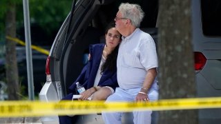 A man comforts a young woman wearing a graduation gown within the crime scene of a shooting at Xavier University in New Orleans, Tuesday, May 31, 2022.