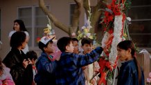 Students at Cleveland Elementary School in Stockton, Calif., look at a wreath, Jan. 19, 1989, that was placed in front of the school in memory of the five children who were killed by a gunman in a nearby yard, Jan. 17.