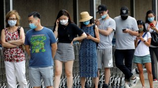 People wear protective face masks outside at a shopping plaza after New Jersey Governor Phil Murphy said he would sign an executive order requiring people to wear face coverings outdoors to prevent a resurgence of the coronavirus disease (COVID-19), in Edgewater, New Jersey, July 8, 2020.