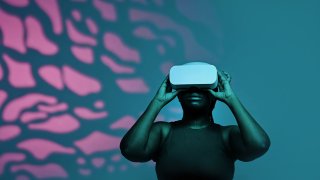 A Black woman wears a virtual reality headset.