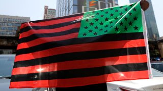 A man holds an African-American flag