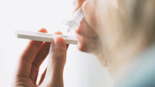 Close up of medical professional placing liquid drops into antigen test strip