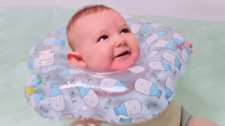 A baby in a tub using a neck float.