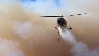 A helicopter drops water on the Hesperia Fire.
