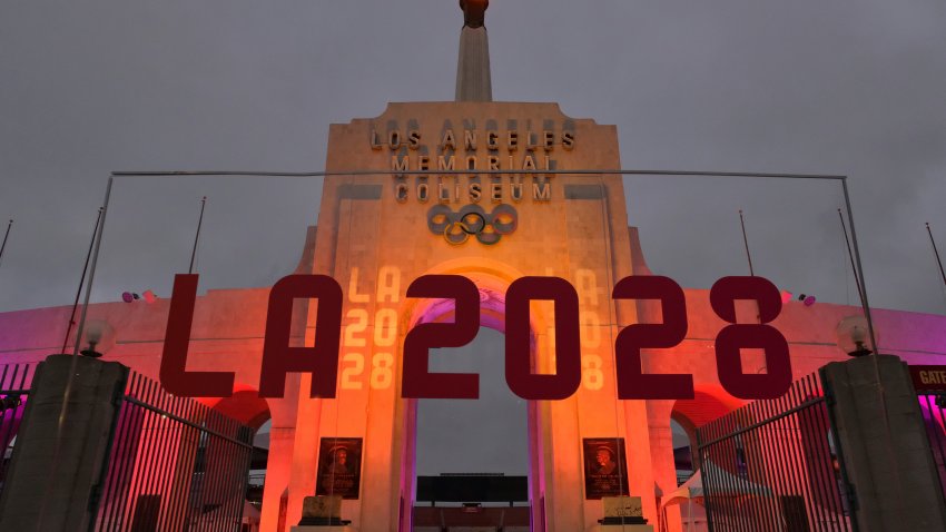 In this Sept. 13, 2017, file photo, an LA 2028 sign is seen in front of a blazing Olympic cauldron at the Los Angeles Memorial Coliseum.