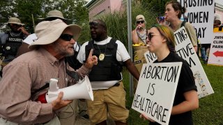 A clinic security officer, left, attempts to keep anti-abortion activist Doug Lane, left, from a physical confrontation