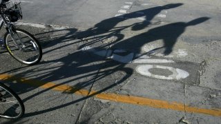 Shadows of bicyclists are thrown on the beach bike path in Los Angeles.